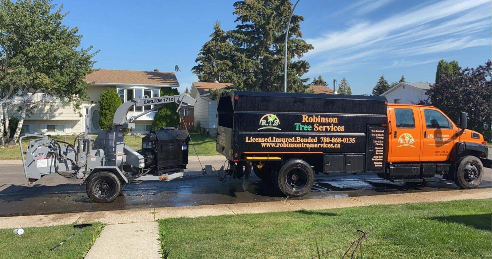 Robinson Tree Services branded orange truck and wood chipper on a job site